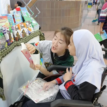 Young Malaysian girl smiling with stack of colorful storybooks